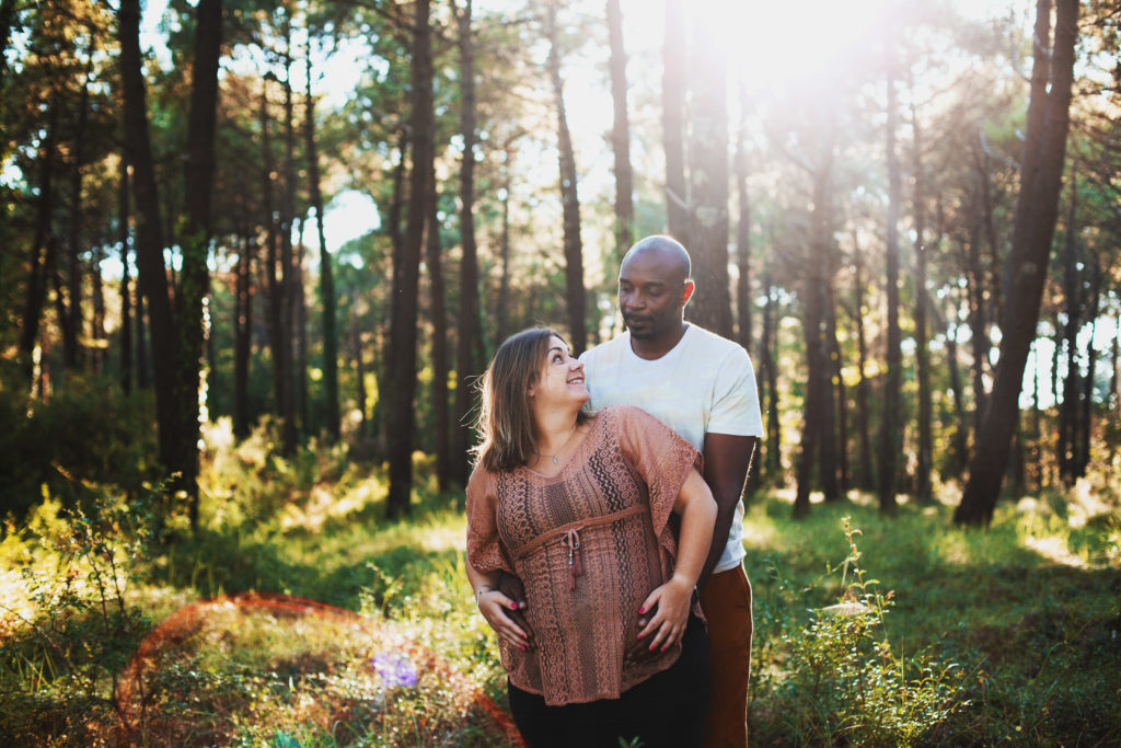 Femme enceinte et homme noir se regardent dans une fôret pendant le coucher de soleil