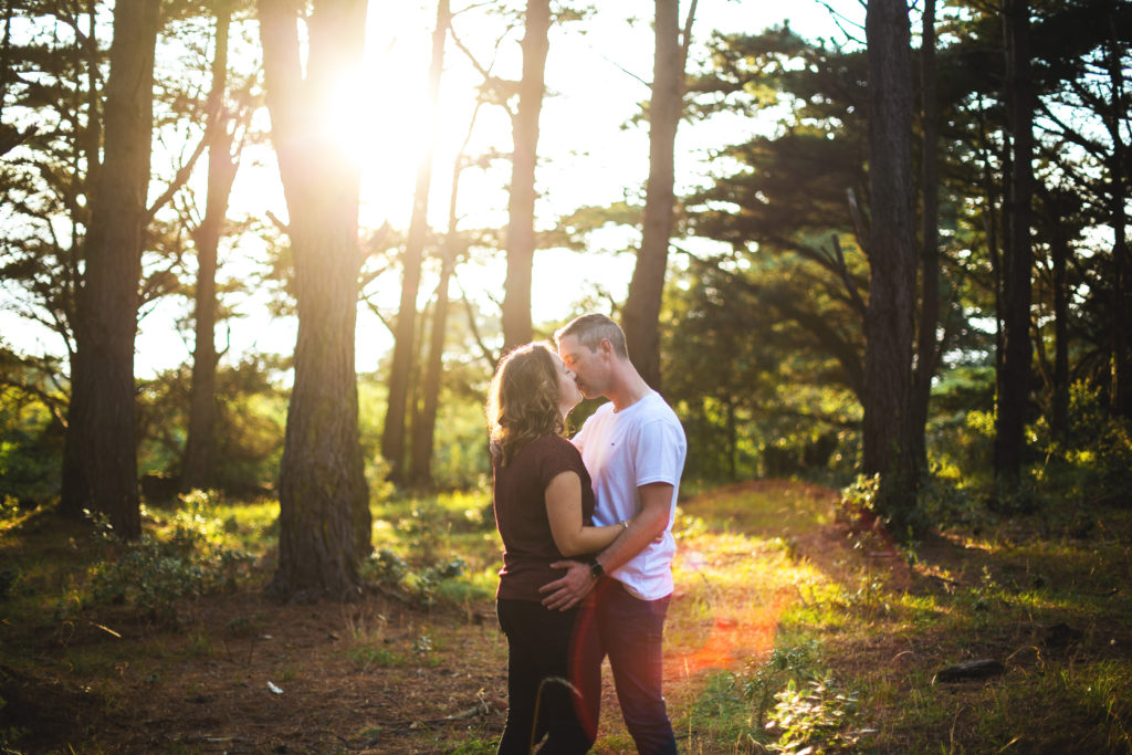 Couple s'embrassant dans une fôret lors d'un coucher de soleil