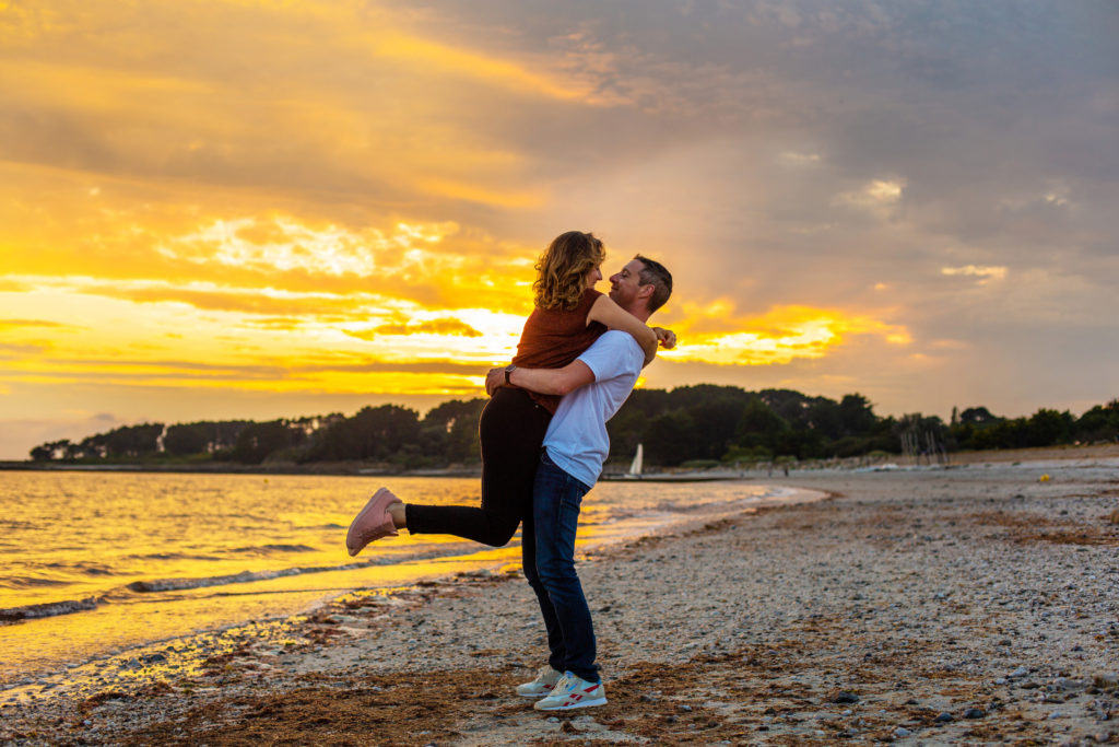 Une femme se jetant dans les bras de son homme sur la plage pendant le coucher de soleil